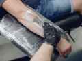 Nowy tatuaż na przedramieniu, artysta w rękawiczce nakłada piankę. Pytanie: nowy tatuaż jak długo nosić folię?