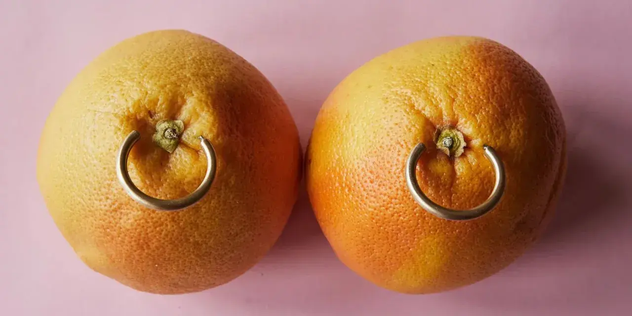 Dwa grejpfruty z kółkami imitującymi, ile goi się kolczyk w sutku.