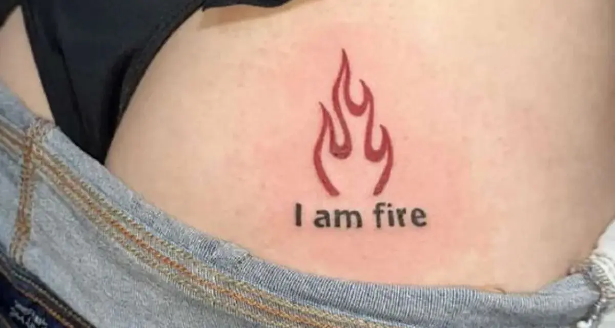 Płomień i napis "I am fire" na skórze, widoczne w okolicach biodra, tuż nad dżinsami. Ten tatuaż na dupie mówi sam za siebie.