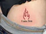 Płomień i napis "I am fire" na skórze, widoczne w okolicach biodra, tuż nad dżinsami. Ten tatuaż na dupie mówi sam za siebie.