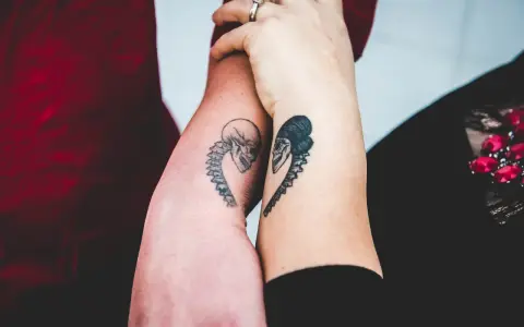 Dwa ramiona z tatuażami czaszek w kształcie serca, symbolizujące tatuaż dla niej i dla niego.