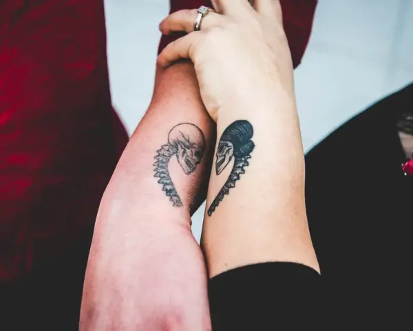 Dwa ramiona z tatuażami czaszek w kształcie serca, symbolizujące tatuaż dla niej i dla niego.