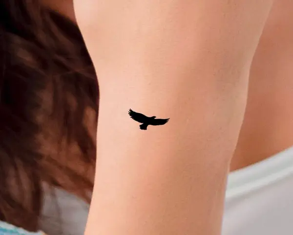 Mały tatuaż orzeł w locie na skórze. Symbol wolności i siły.