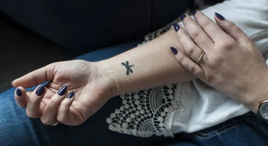 Delikatny tatuaż ważki na nadgarstku, subtelny akcent, który może być interpretowany jako tatuaż erotyczny.