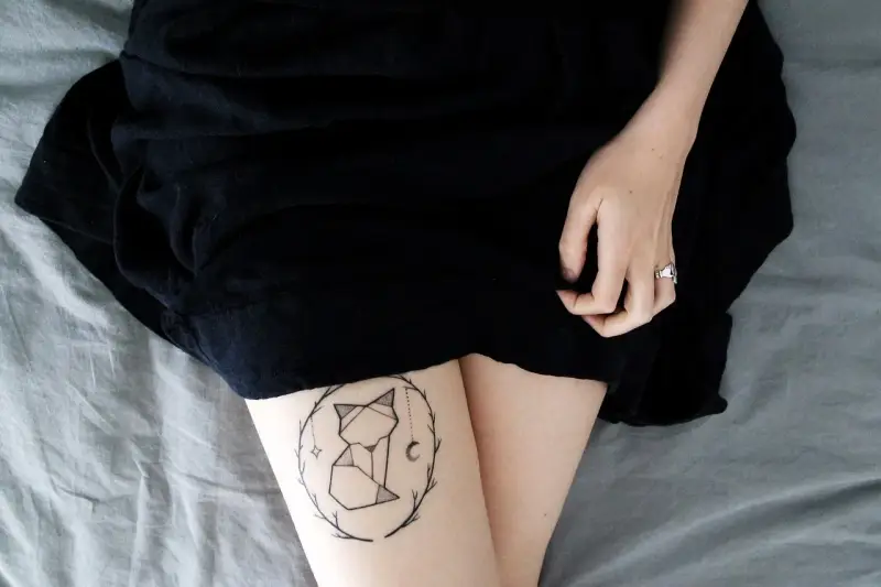 Geometryczny tatuaż lisa w okręgu gałązek. Nawet tatuaż po 30 latach wygląda świetnie.